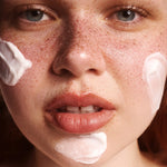 Close-up of a person's face with The Body Shop Vitamin E Day Cream on their cheeks and chin.